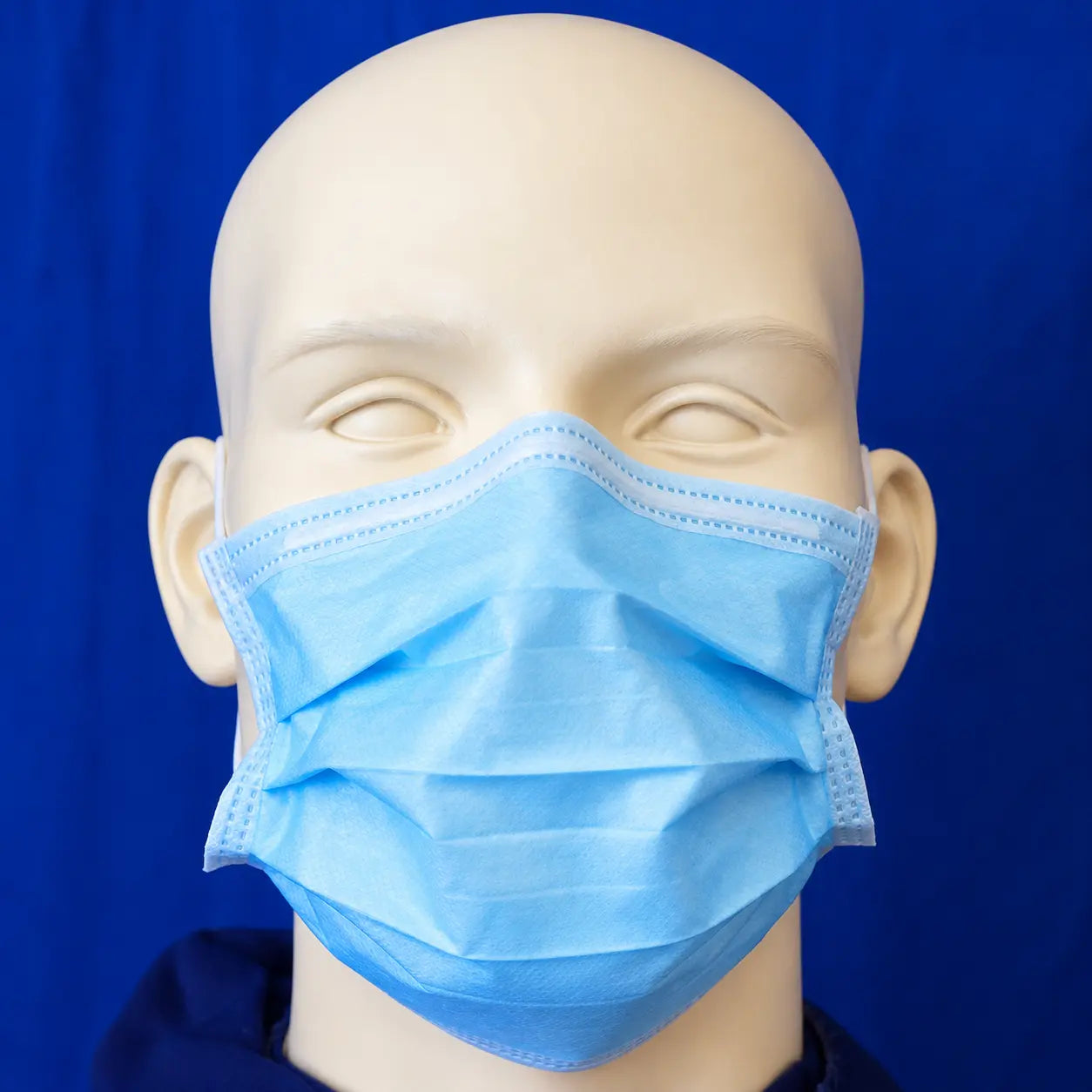 Blue 3-ply disposable medical face mask with ear loops shown on a mannequin head.